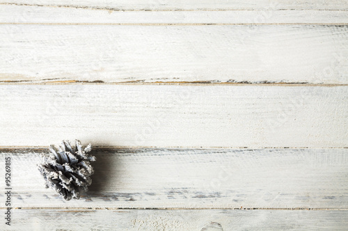 White pine cone on bottom left, on wooden table as background with copy space