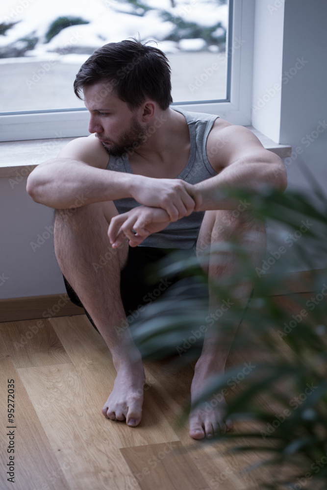 Obraz premium Sad man sitting on the floor