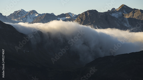 Morgendliche Nebelschwaden fliessen über eine Talstufe ins Stillachtal in den Allgäuer Alpen bei Oberstorf in Bayern photo