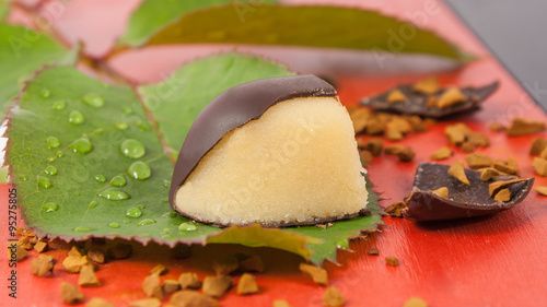 Marzipan orange chocolate candy on a green leaf photo