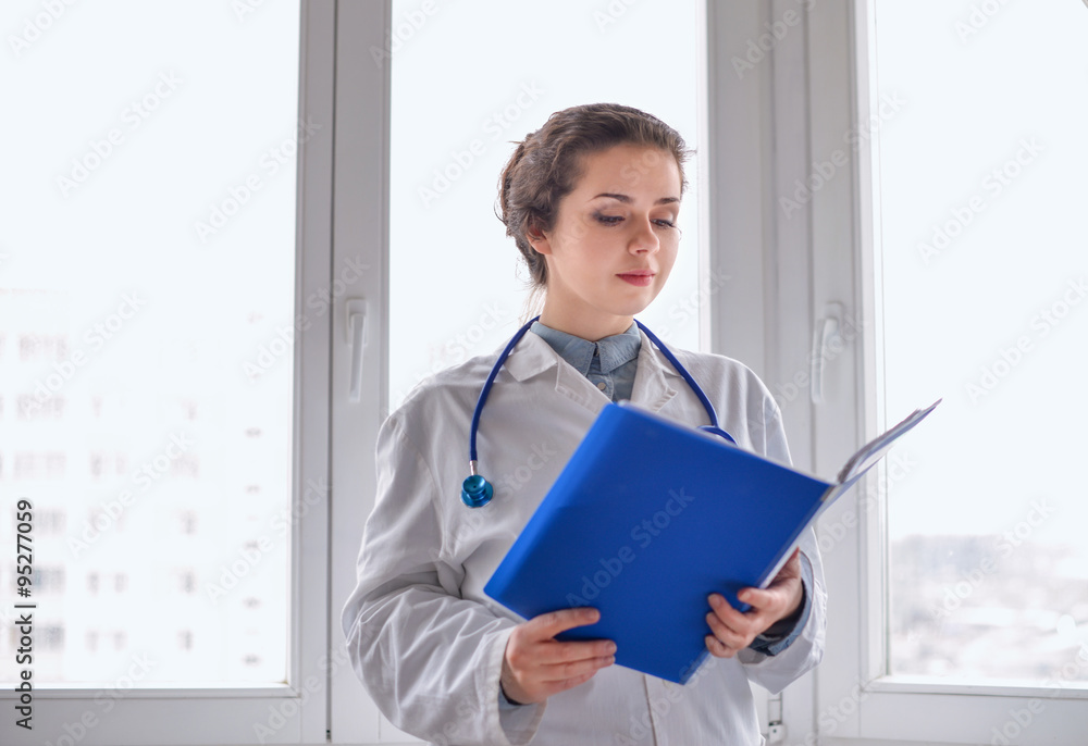 Woman doctor standing with folder at hospital Woman doctor standing with folder at hospital
