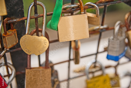 Shiny padlock of lovers hang on bridge railings photo