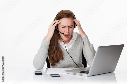 desperate 20s working woman under shock with headset and computer