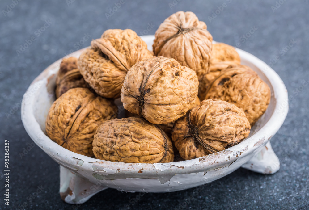 Walnuts in a white bowl on a black background Walnuts in a white bowl on a black background