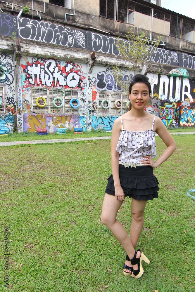 Portrait of thai adult beautiful girl relax and smile on graffiti wall