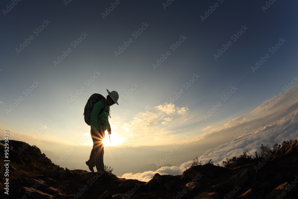 silhouette of backpacker hiking on sunset mountain peak