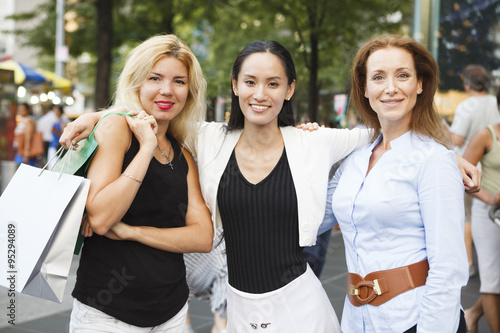 Three happy women arms around shoulders. Focus on center woman.