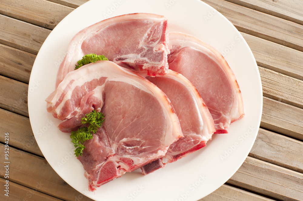 Four raw pork cutlets on a plate Four raw pork cutlets on a plate
