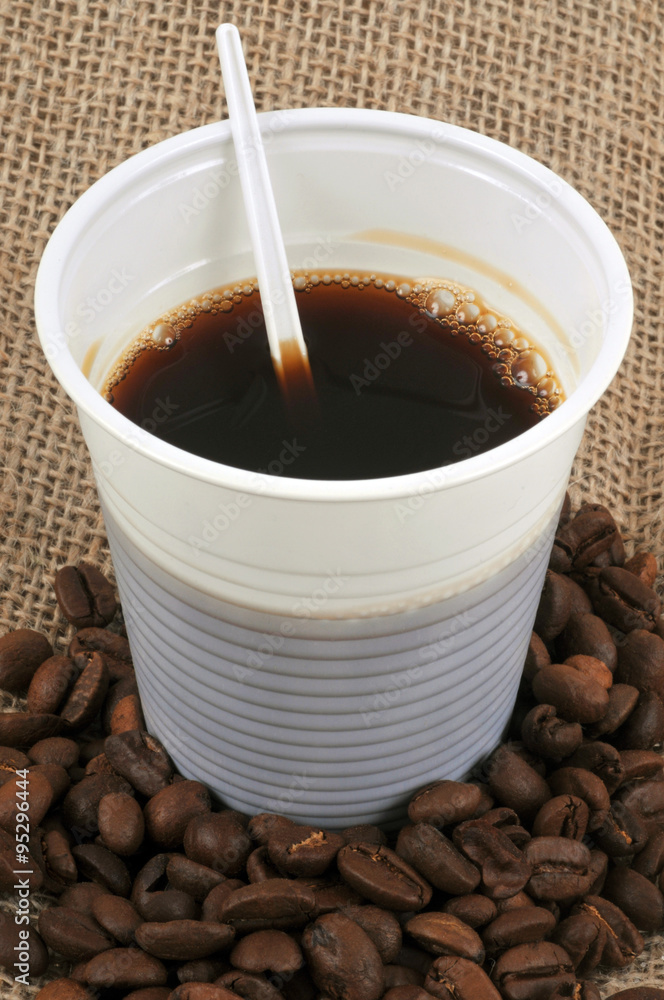 Le gobelet de café noir et des grains de café Photos