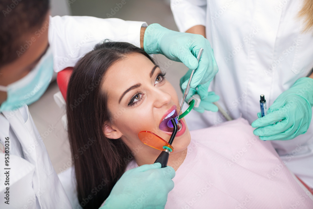 dentist is treating teeth of the female patient dentist is treating teeth of the female patient