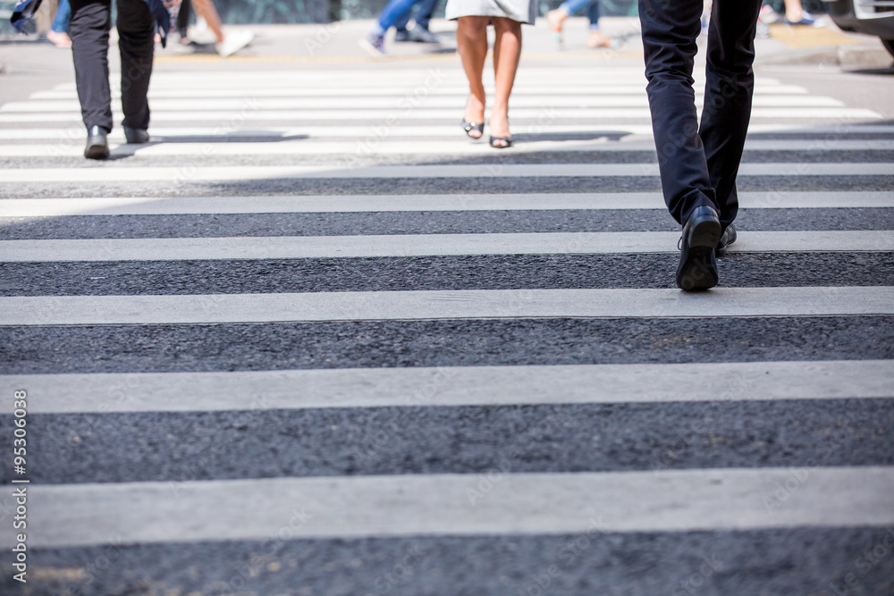 Pedestrian in business suits crossing on the road, feet rushing through the zebra traffic walk way Pedestrian in business suits crossing on the road, feet rushing through the zebra traffic walk way