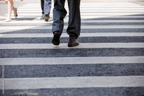 Pedestrian in business suits crossing on the road  feet rushing through the zebra traffic walk way