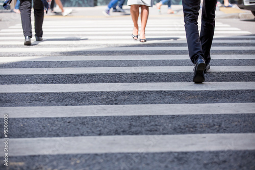 Pedestrian in business suits crossing on the road, feet rushing through the zebra traffic walk way