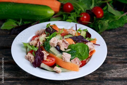 Tuna salad with Spinach, rocket, red ruby chard, tomatoes, cucumbers, carrot, red onion, on old wooden table