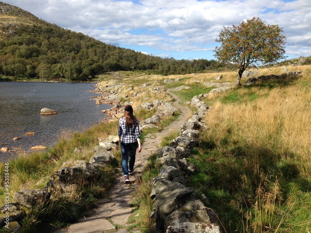 Girl hiking on a stone trail towards Dalsnuten hill, Sandnes, Norway. Daytime hike in Norwegian landscape.