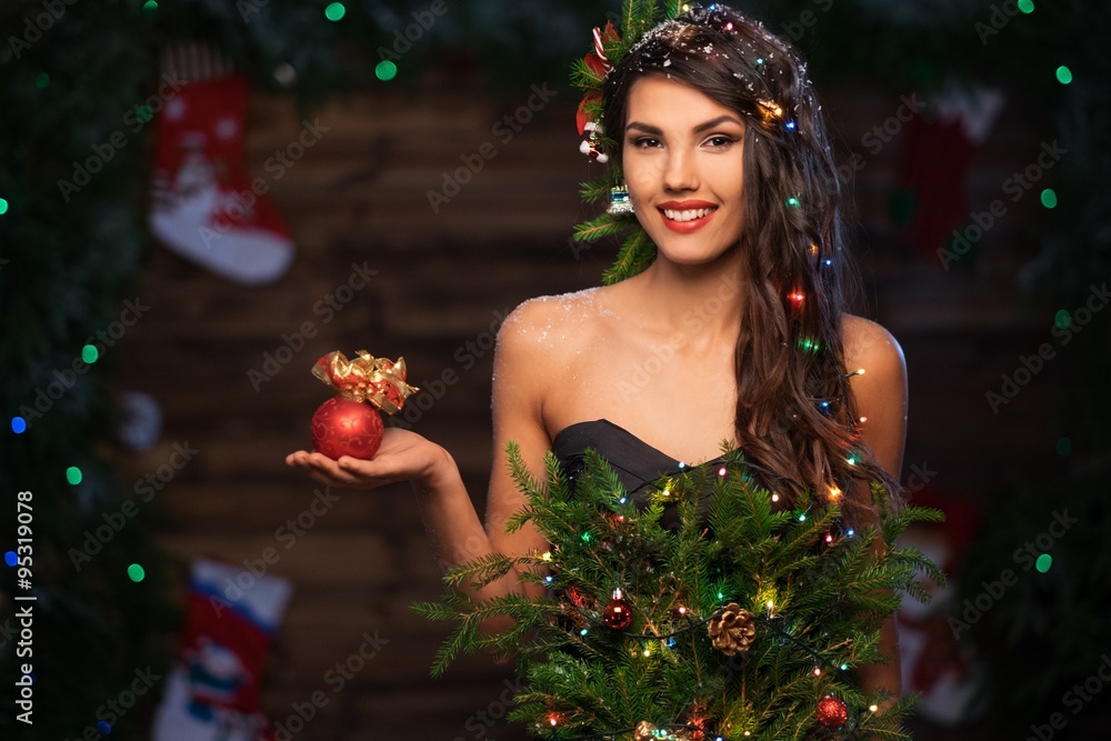 Woman in christmas tree dress in wooden interior holding christmas toy