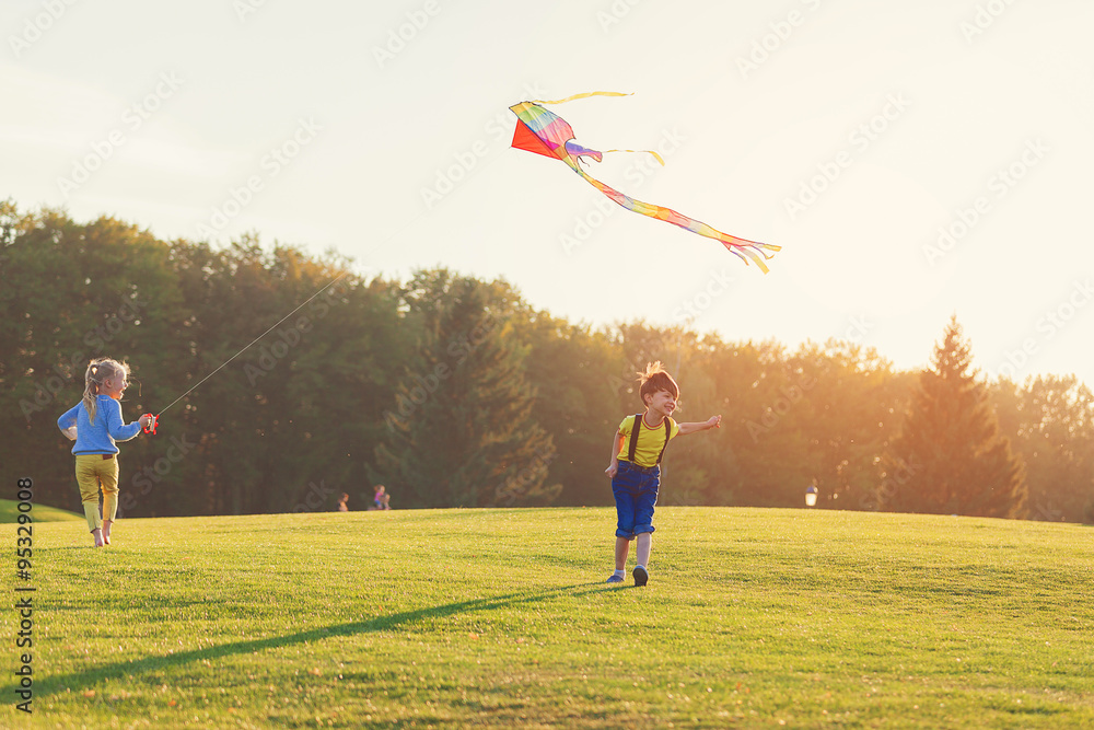 Two kids flies a kite over sunset in park Two kids flies a kite over sunset in park