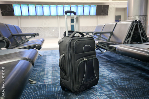 Black suitcase is left or lost at an airport hall.