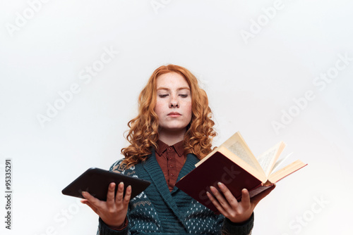 studio shot of redhead girl with ebook and book on white background. Old vs modern. Education concept