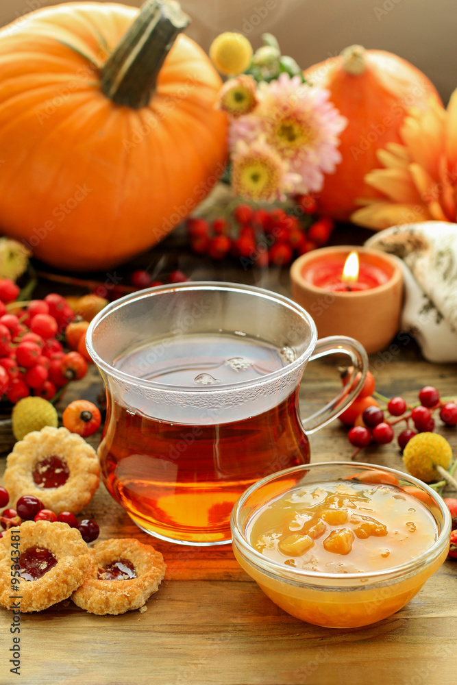 Glass of hot steaming tea, bowl of peach jam and autumn plants Glass of hot steaming tea, bowl of peach jam and autumn plants