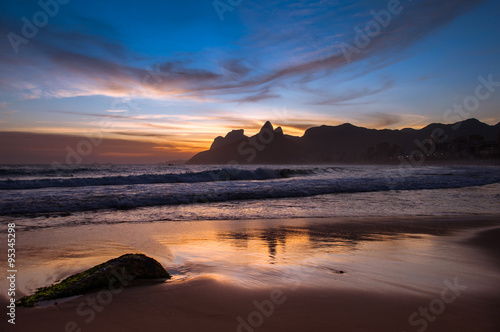 Sunset in Ipanema Beach in Rio de Janeiro, Mountains in the Horizon are Reflected in Wet Sand