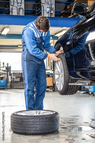 Mechanic Pressing Gauge Into Tire Tread In Garage © corepics