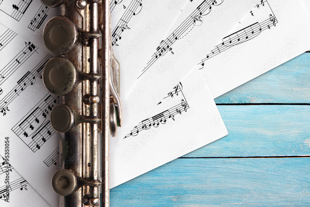 Obraz premium Old flute with sheet music on blue wooden boards