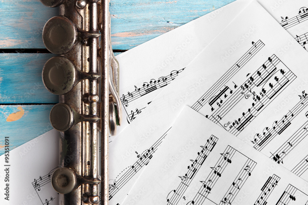 Obraz premium Old flute with sheet music on blue wooden boards