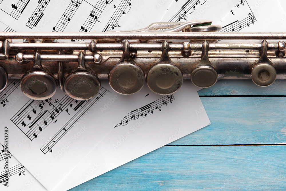 Obraz premium Old flute with sheet music on blue wooden boards
