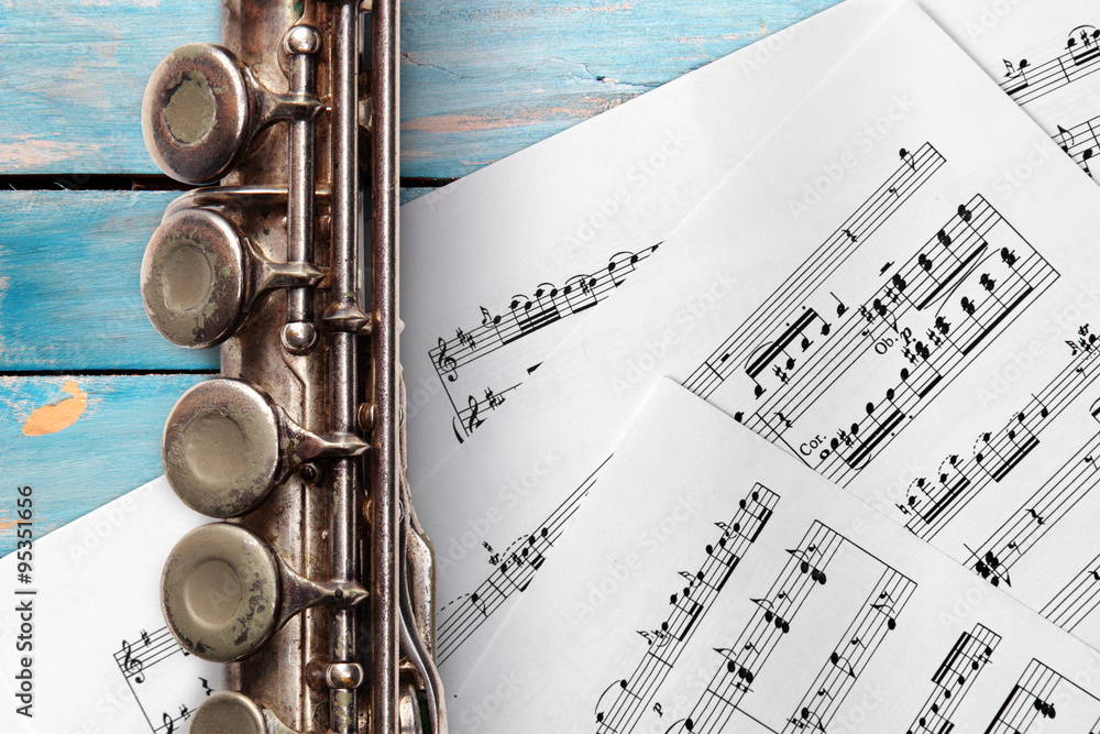 Obraz premium Old flute with sheet music on blue wooden boards