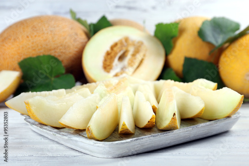 Ripe melons with green leaves on wooden table close up