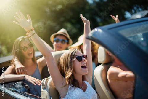 young people having fun in a black convertible by a sunny day