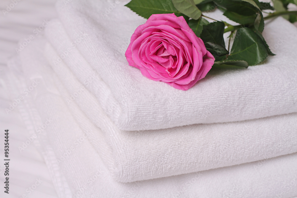 Stack of white and soft hotel towels decorated with rose flower. Perfect white laundry. Honeymoon concept Stack of white and soft hotel towels decorated with rose flower. Perfect white laundry. Honeymoon concept
