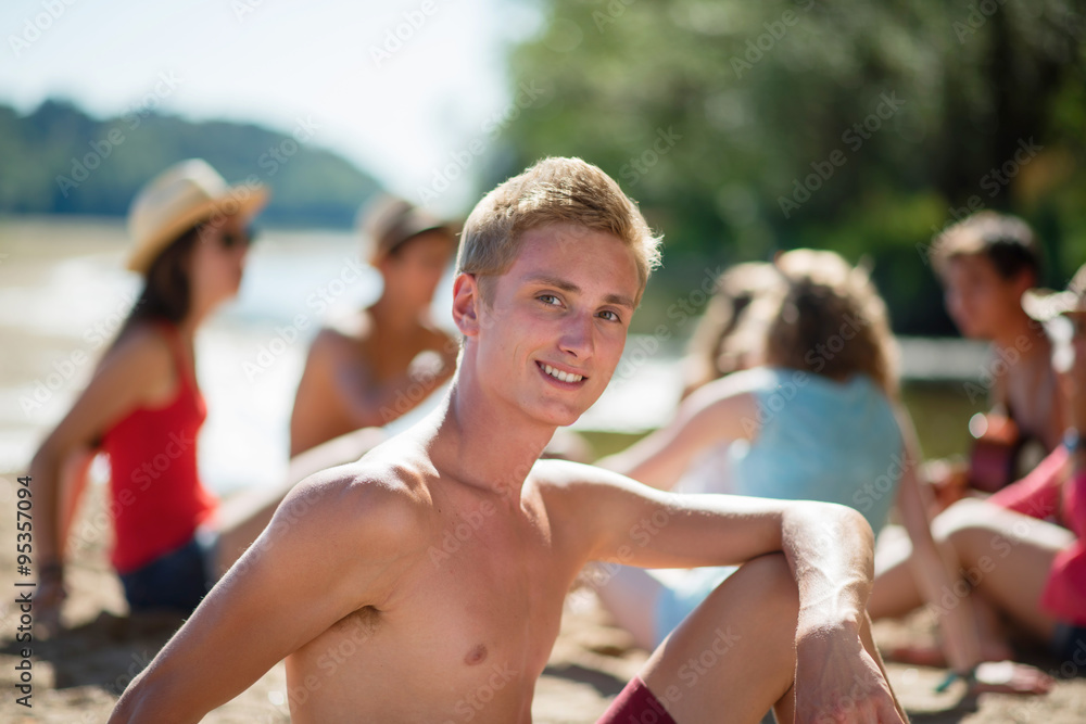 Focus on a good looking blond teenager, sitting on the sand Focus on a good looking blond teenager, sitting on the sand