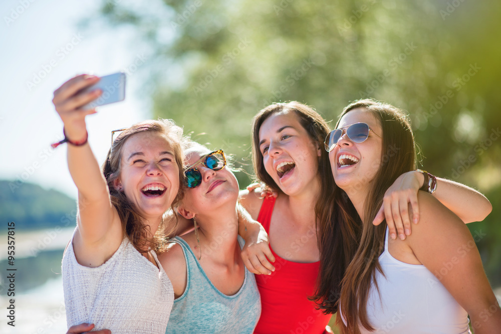 Focus on four girlfriends taking selfies on a smartphone Focus on four girlfriends taking selfies on a smartphone