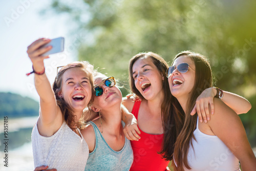 Focus on four girlfriends taking selfies on a smartphone 