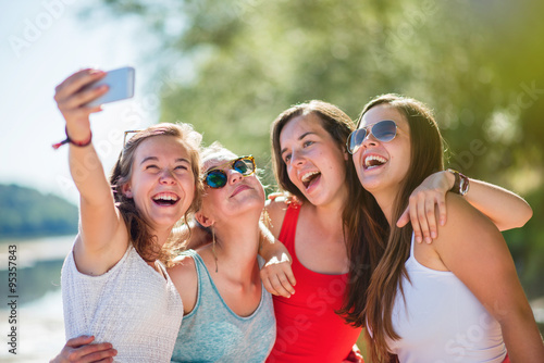 Focus on four girlfriends taking selfies on a smartphone 