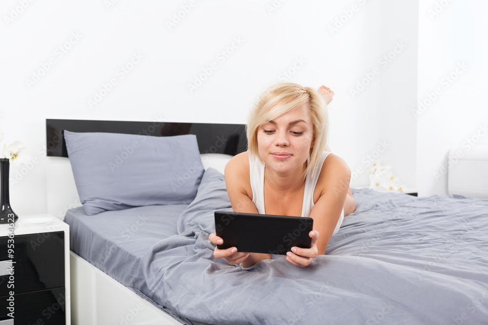 beautiful woman lying on bed using digital tablet beautiful woman lying on bed using digital tablet