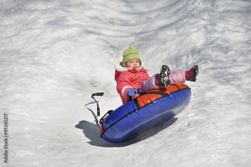 A little girl up in the air on a tube sledding in the snow 
