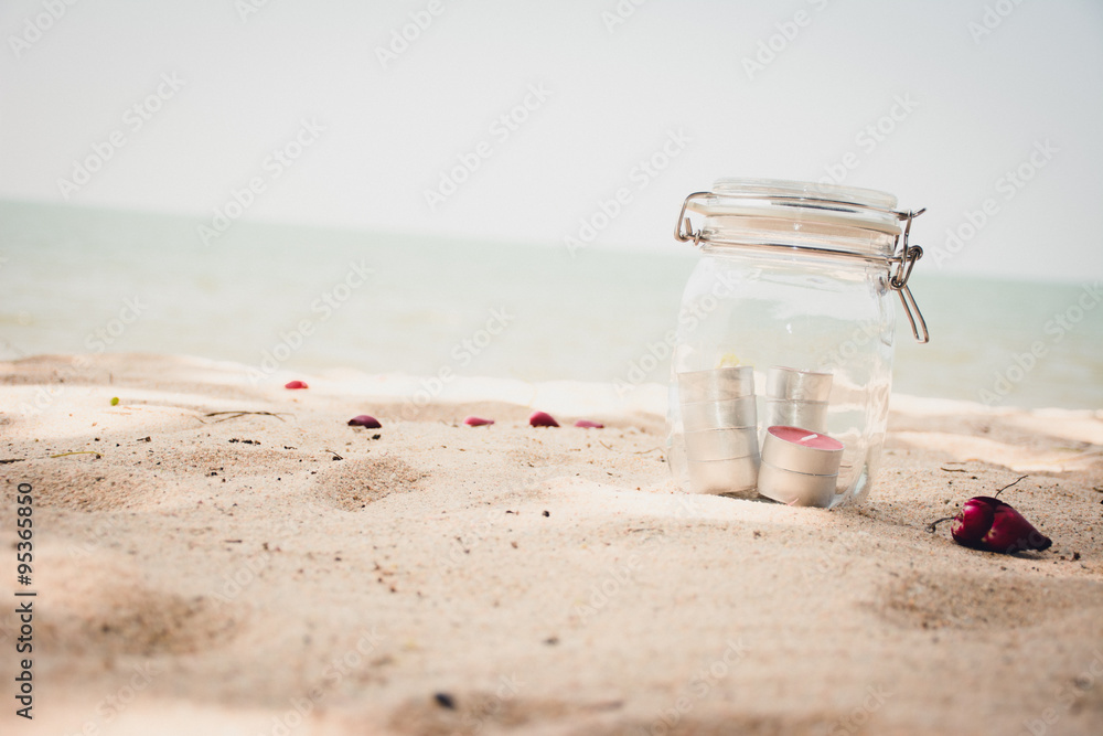 Candles in jar with beautiful beach and sea in background. - vin