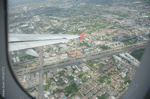 Bangkok town as seen through window of an aircraft. Wing of the