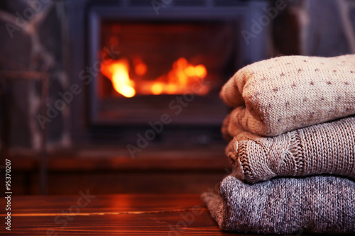 Knitted clothes on table on fireplace background