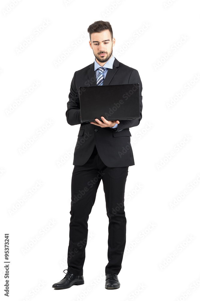 Front view of young bearded corporate man working on laptop. Full body length portrait isolated over white studio background. Front view of young bearded corporate man working on laptop. Full body length portrait isolated over white studio background.