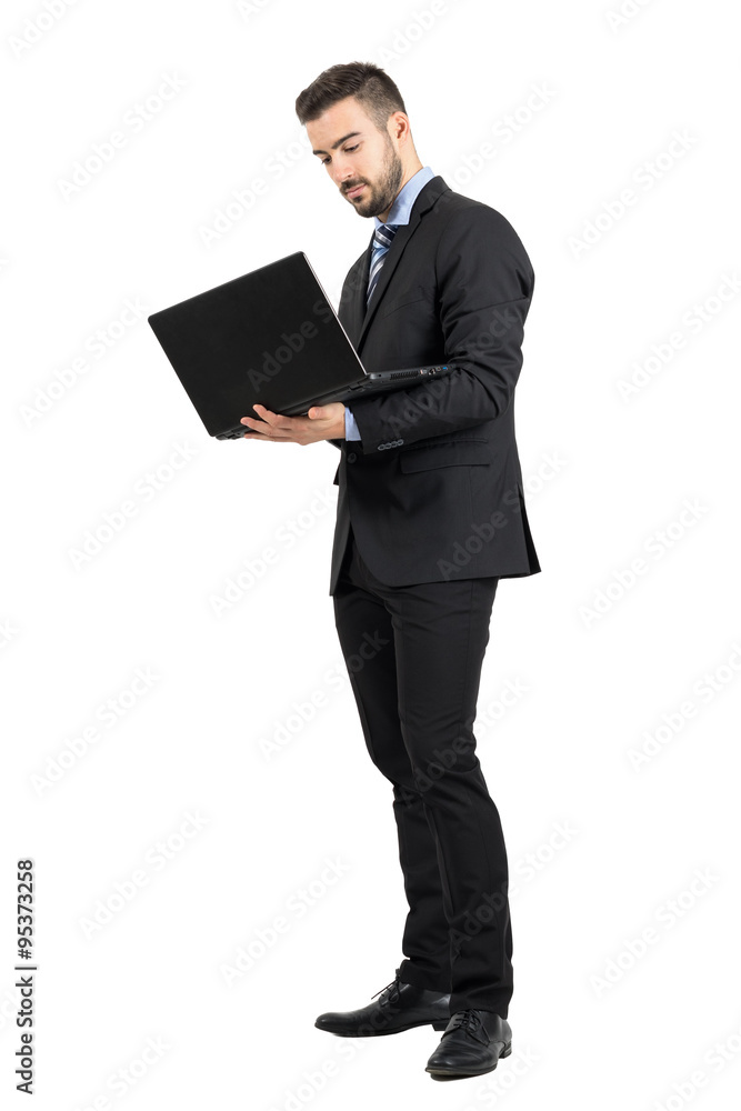 Young standing business man working on a laptop. Full body length portrait isolated over white studio background. Young standing business man working on a laptop. Full body length portrait isolated over white studio background.