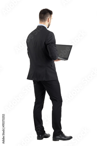 Rear view of young man in suit using laptop. Full body length portrait isolated over white studio background. 