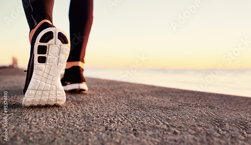 Runner man feet running on road closeup on shoe. Male fitness athlete jogger workout in wellness concept at sunrise. Sports healthy lifestyle concept. photo