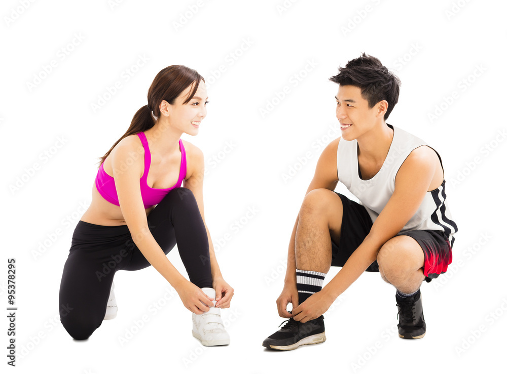 happy young couple tying sports shoes happy young couple tying sports shoes