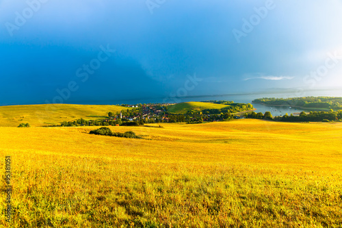 Beautiful landscape, green and yellow meadow and lake with village. Slovakia, Central Europe.