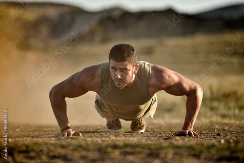 athletic young man exercising outdoor on dusty field
