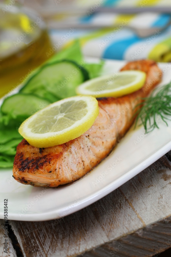 Grilled salmon with slices of lemon and green side salad

